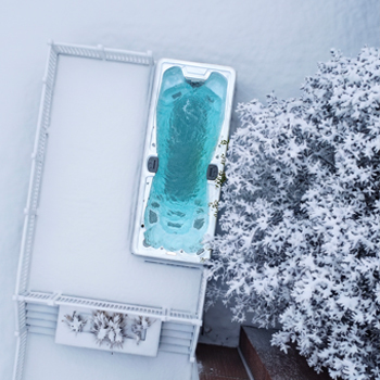 Een drone-opname van een zwemspa die in de winter in werking is, omringd door sneeuw.