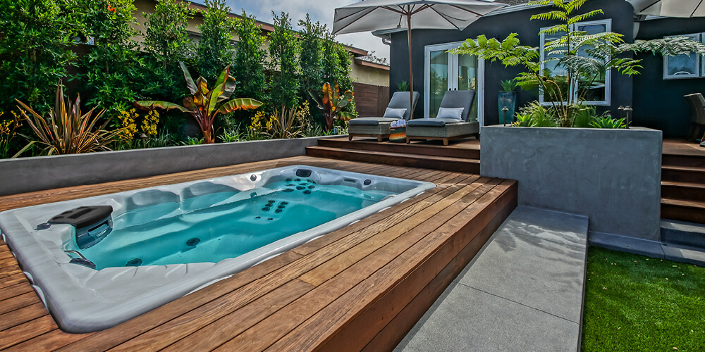 Zonneparaplu’s en ligstoelen rondom een Therapool-zwemspa.