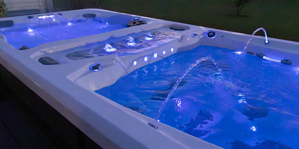 Uitzicht op een zwemspa ’s nachts, met waterpartijen en ingeschakelde leds.